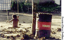Child plays next to Texaco oil drum
